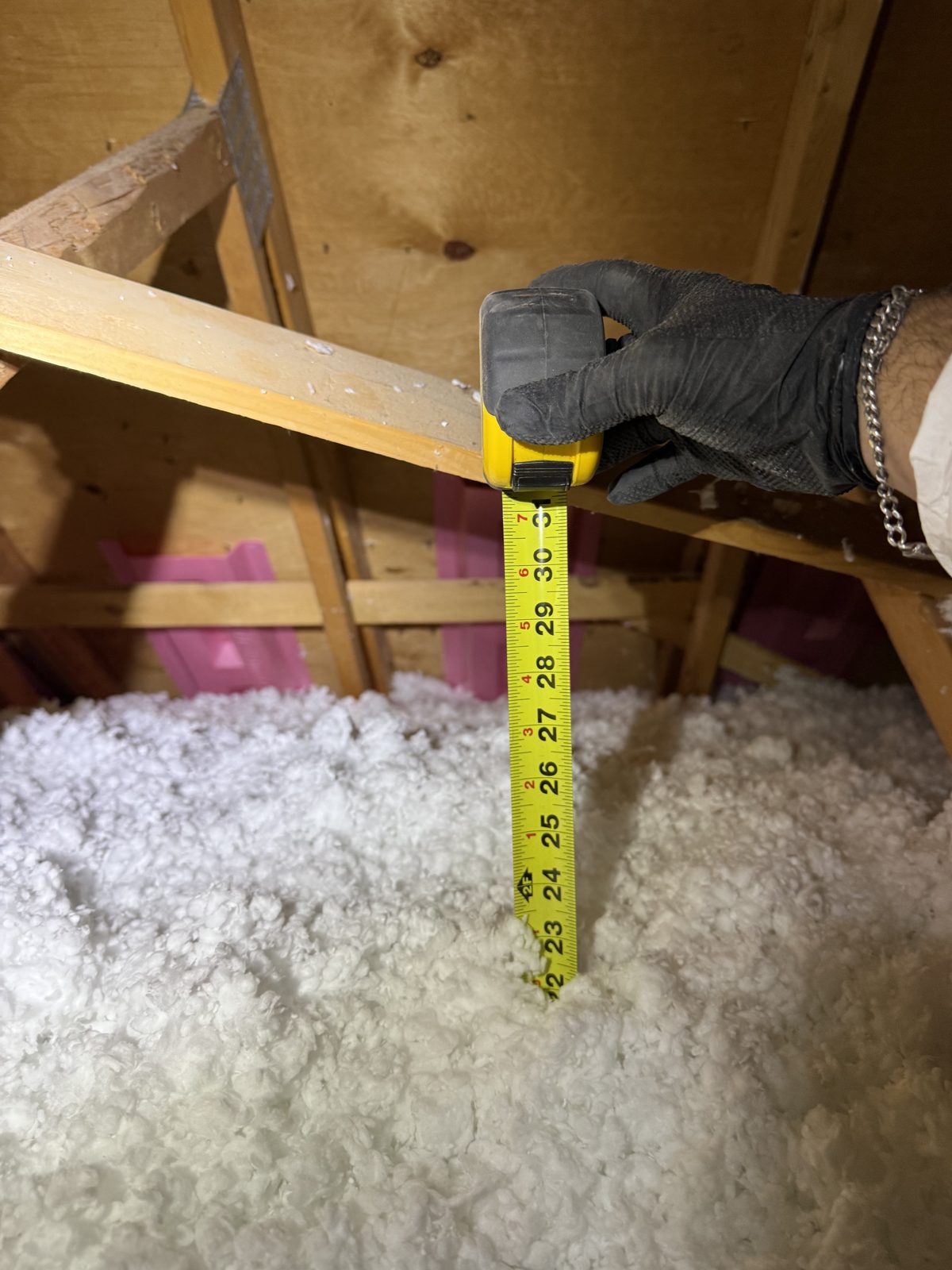 Depth marker in a finished attic showing 22 inches of blown insulation, meeting the R-60 standard