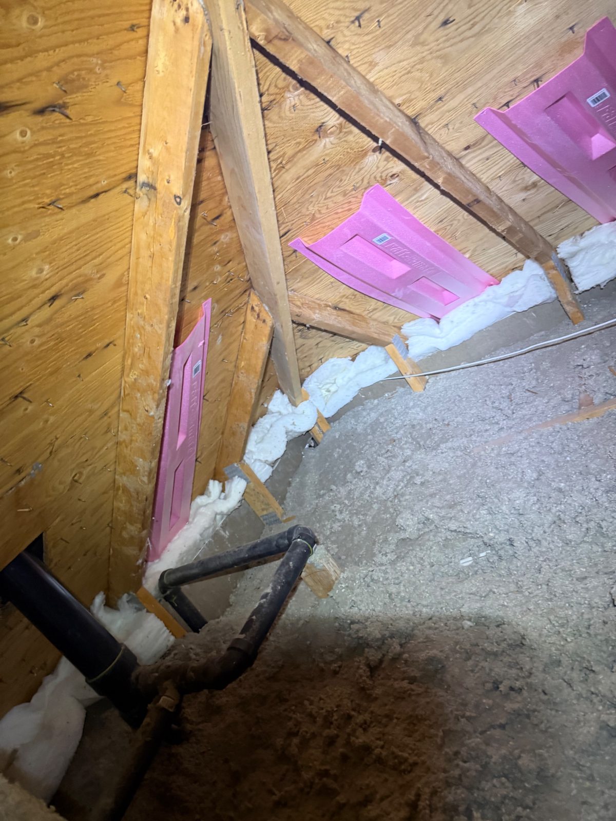 Baffles at the rafter bays holding the soffit airway open — installed before the blow-in, with the top plates spray-foam sealed.