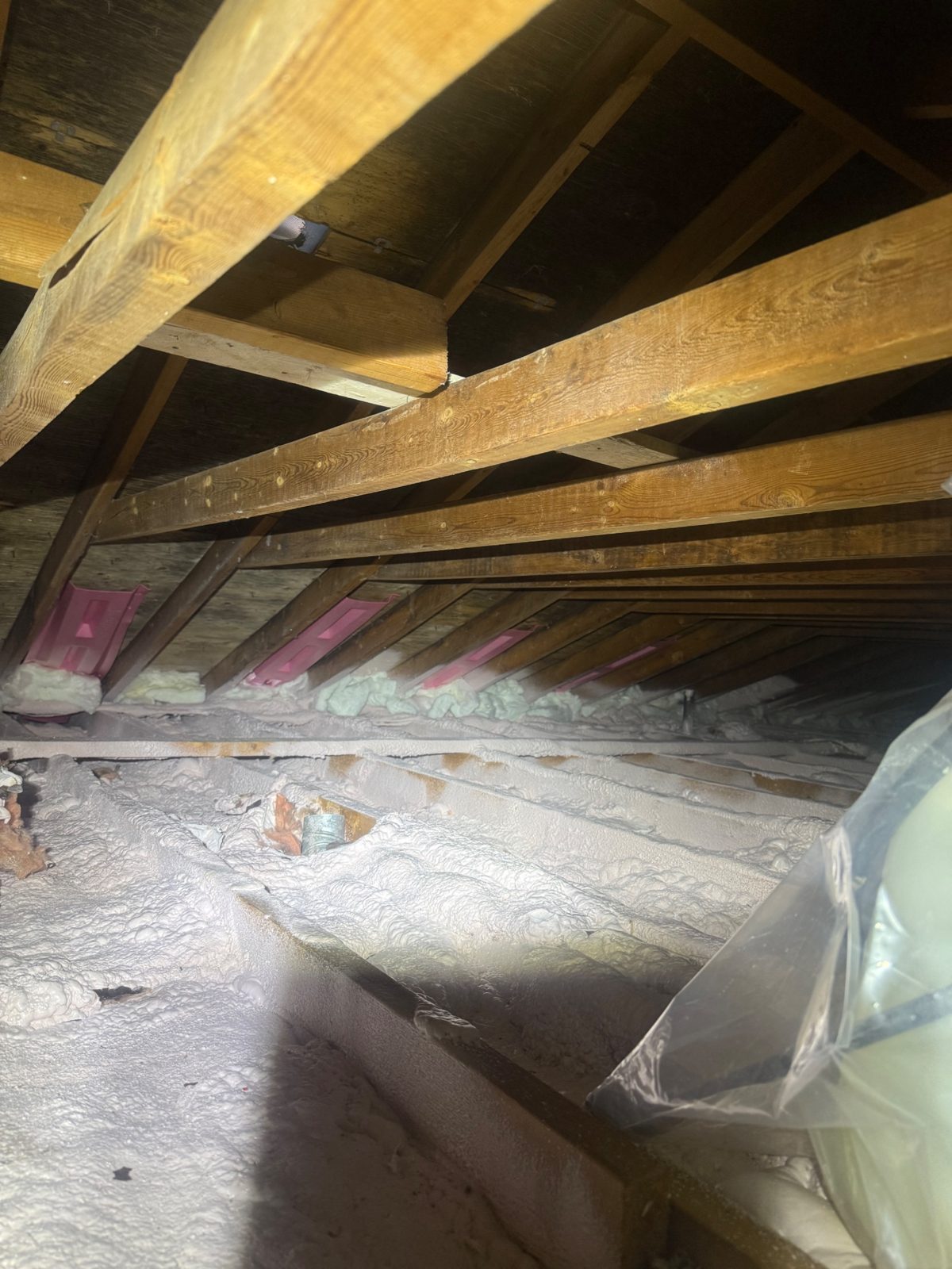 Step 3 &mdash; the rebuild in one frame: 2&Prime; of closed-cell spray foam sealing the entire attic floor, with new baffle vents foam-sealed at every eave bay.