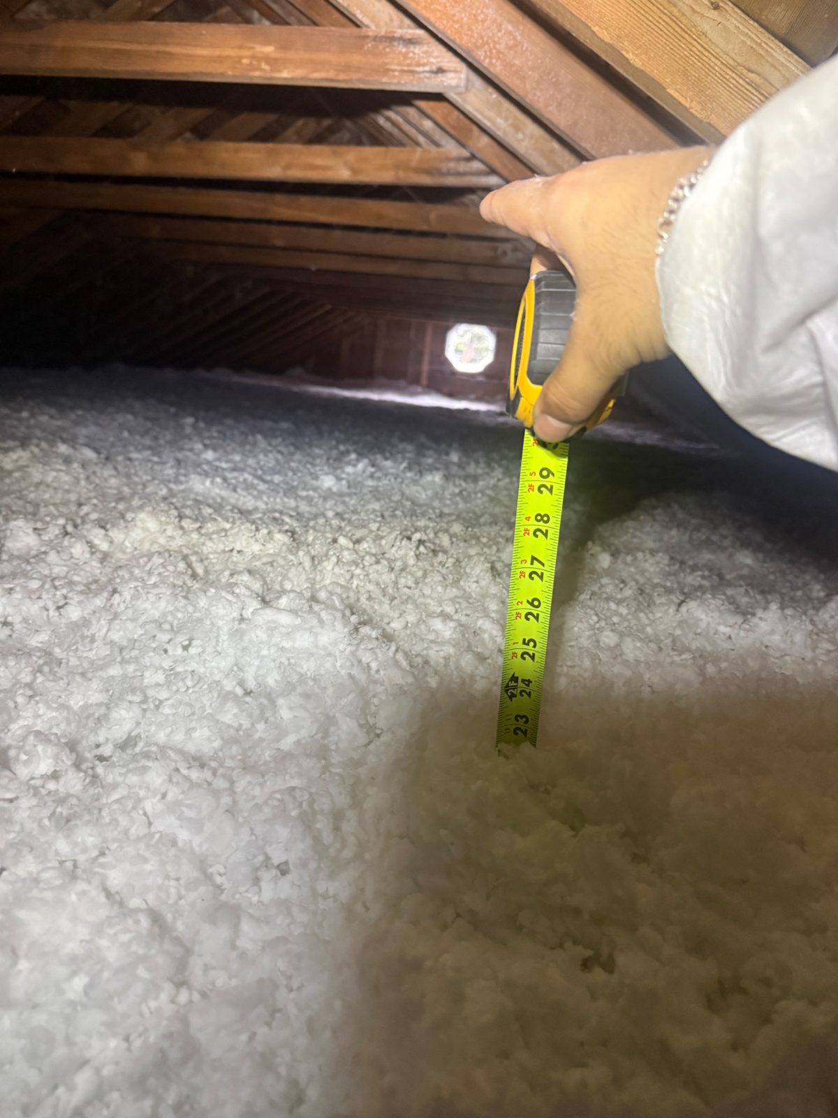 Step 3 — the tape disappears at 23″: fresh blown-in fiberglass past the R-60 mark.